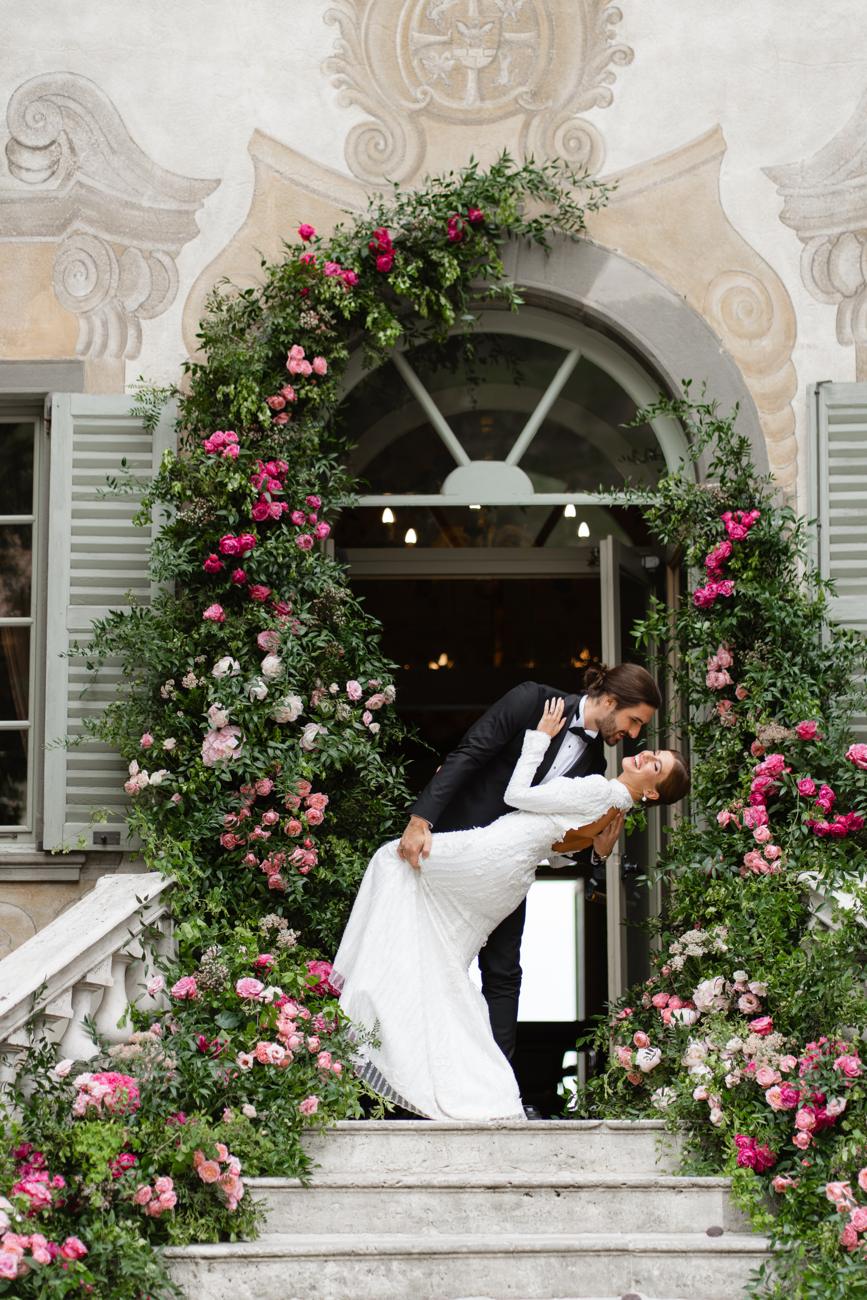 A dip kiss under an arch of roses